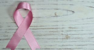 ruban rose symbôle de la lutte contre le cancer du sein, déposé sur une table blanche en bois