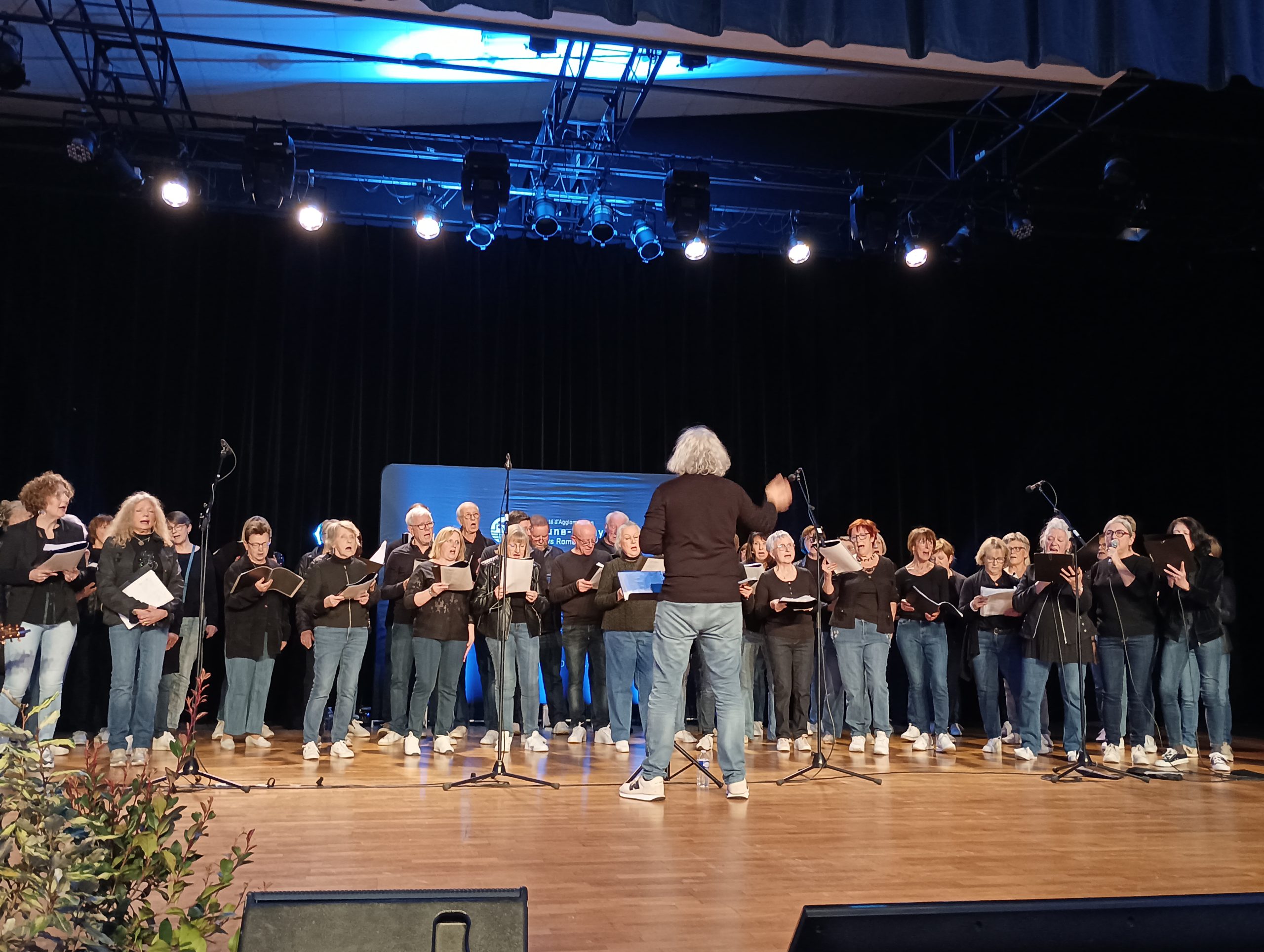 une chorale sur scène avec son chef d'orchestre le dos tourné lors de la cérémonie des voeux de la Cabbalr à l'espace françois Mitterand. 